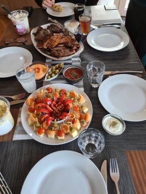 Köy ahşap masada ızgara et ve sebzelerle servis edilen peynir tabağı.