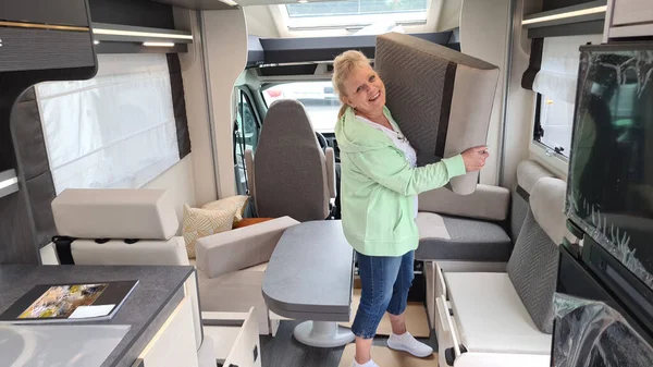 Young blond woman setting up her new motorhome campervan. The brand new mobile home is set up