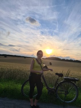 Yazlık şehir parkında bisiklet süren genç bir kadın. Aktif insanlar. Hippi kız rahatla ve bisiklete bin. Yaz günü işe bisikletle gitmek. Bisiklet ve ekoloji yaşam tarzı kavramı