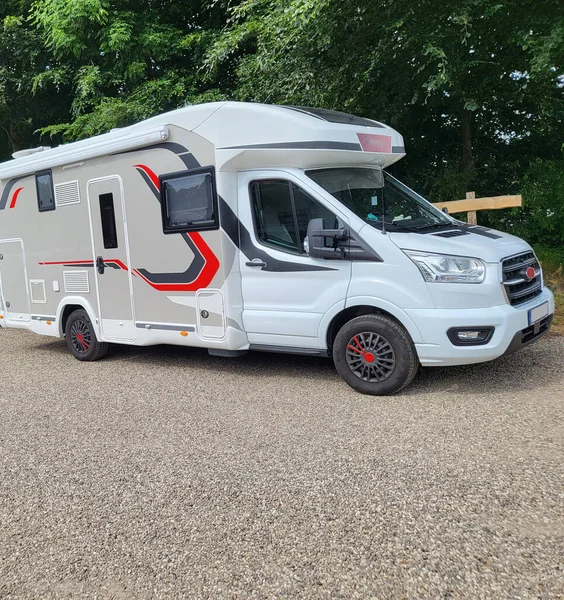 Mobile home with awning and awning and camping table with chairs on the campsite