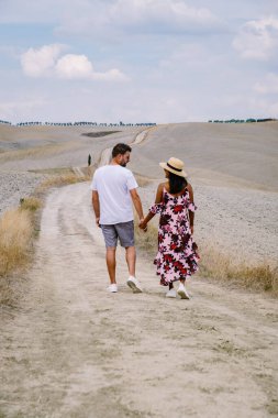 Tuscany manzarası, tahıl tarlaları, selvi ağaçları ve gün batımında tepelerde evler. Tuscany, İtalya, Avrupa, İtalya, Tarım Bakolenosu 'nda kıvrımlı yolu olan yaz kırsal arazisi 