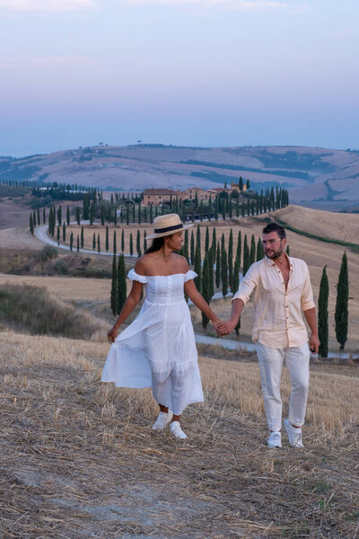 Тосканский пейзаж с зерновыми полями, кипарисами и домами на холмах на закате. Летний сельский пейзаж с изогнутой дорогой в Тоскане, Италия, Европа, Италия, Agriturismo Baccoleno 