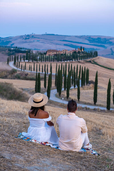 Тосканский пейзаж с зерновыми полями, кипарисами и домами на холмах на закате. Летний сельский пейзаж с изогнутой дорогой в Тоскане, Италия, Европа, Италия, Agriturismo Baccoleno 