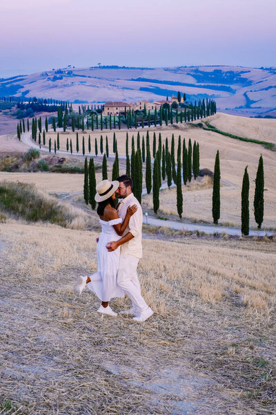 Тосканский пейзаж с зерновыми полями, кипарисами и домами на холмах на закате. Летний сельский пейзаж с изогнутой дорогой в Тоскане, Италия, Европа, Италия, Agriturismo Baccoleno 