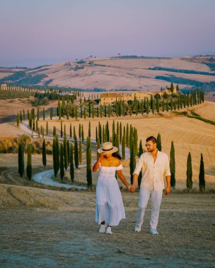 Toskana, Girit Senesi kırsal günbatımı manzarası. Köy çiftliği, selvi ağaçları, yeşil alan, güneş ışığı ve bulut. İtalya, Avrupa ve Tuscany, İtalya ve Avrupa 'da kıvrımlı yolu olan yaz kırsal arazisi