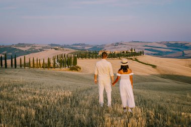 Toskana, Girit Senesi kırsal günbatımı manzarası. Köy çiftliği, selvi ağaçları, yeşil alan, güneş ışığı ve bulut. İtalya, Avrupa ve Tuscany, İtalya ve Avrupa 'da kıvrımlı yolu olan yaz kırsal arazisi