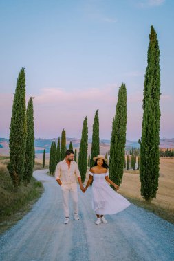 Toskana, Girit Senesi kırsal günbatımı manzarası. Köy çiftliği, selvi ağaçları, yeşil alan, güneş ışığı ve bulut. İtalya, Avrupa ve Tuscany, İtalya ve Avrupa 'da kıvrımlı yolu olan yaz kırsal arazisi