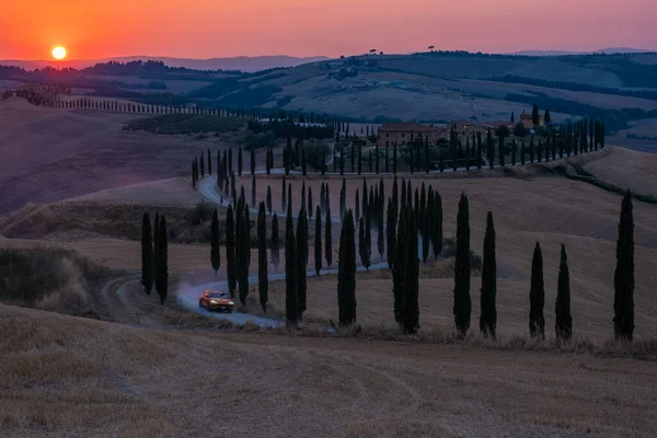 Toscane, Kreta Senesi landelijk zonsondergang landschap. Platteland boerderij, cipressen bomen, groen veld, zonlicht en wolken. Italië, Europa, Zomer landelijk landschap met gebogen weg in Toscane, Italië, Europa — Stockfoto