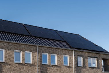 Güneşli bir gökyüzüne bağlı güneş panelleri olan yeni evler inşa edin. Siyah güneş panelleri olan yeni binaları kapatın. Zonnepanelen, Zonne enerjisi, Çevirisi: Güneş paneli, Güneş Enerjisi