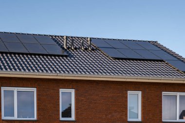 Güneşli bir gökyüzüne bağlı güneş panelleri olan yeni evler inşa edin. Siyah güneş panelleri olan yeni binaları kapatın. Zonnepanelen, Zonne enerjisi, Çevirisi: Güneş paneli, Güneş Enerjisi