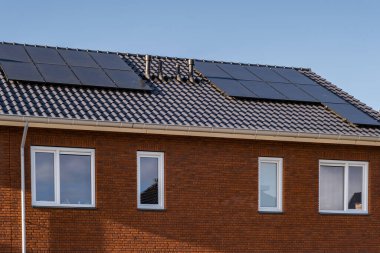 Güneşli bir gökyüzüne bağlı güneş panelleri olan yeni evler inşa edin. Siyah güneş panelleri olan yeni binaları kapatın. Zonnepanelen, Zonne enerjisi, Çevirisi: Güneş paneli, Güneş Enerjisi