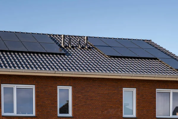 Maisons nouvellement construites avec des panneaux solaires fixés sur le toit contre un ciel ensoleillé Gros plan du nouveau bâtiment avec des panneaux solaires noirs. Zonnepanelen, Zonne energie, Traduction : Panneau solaire,, Énergie solaire — Photo