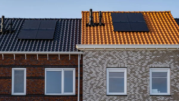 Nybyggda hus med solpaneler fästa på taket mot en solig himmel Närbild av ny byggnad med svarta solpaneler. Zonnepanelen, Zonne energie, Översättning: Solpanel,, Sun Energy — Stockfoto