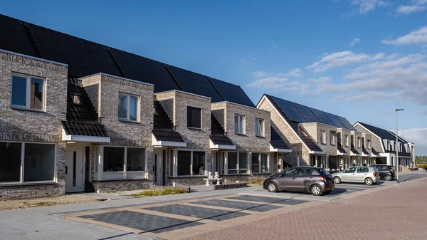 Nově postavené domy se solárními panely připevněnými na střeše proti slunné obloze Zavřít novou budovu s černými solárními panely. Zonnepanelen, Zonne energie, Překlad: Solární panel,, Sun Energy — Stock fotografie