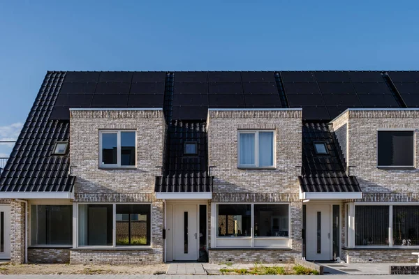 Recém-construir casas com painéis solares ligados no telhado contra um céu ensolarado Fechar-se de novo edifício com painéis solares pretos. Zonnepanelen, Zonne energie, Tradução: Painel solar,, Energia solar — Fotografia de Stock