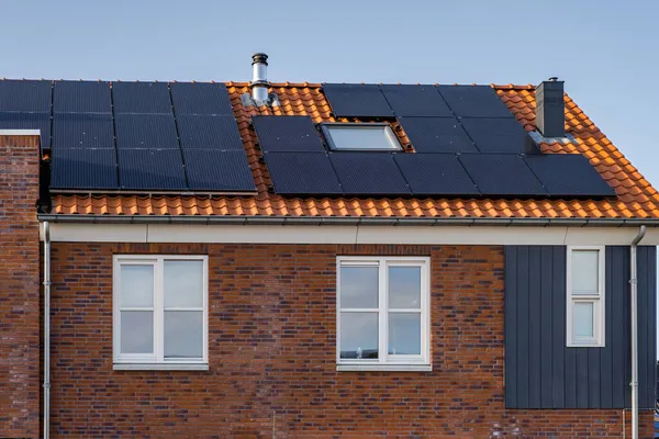 Nybyggda hus med solpaneler fästa på taket mot en solig himmel Närbild av ny byggnad med svarta solpaneler. Zonnepanelen, Zonne energie, Översättning: Solpanel,, Sun Energy — Stockfoto