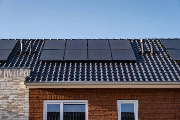 Newly build houses with solar panels attached on the roof against a sunny sky Close up of new building with black solar panels. Zonnepanelen, Zonne energie, Translation: Solar panel, , Sun Energy — Stock Photo, Image