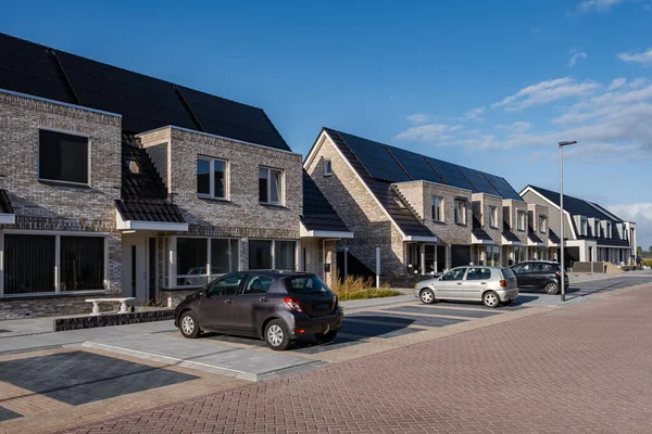 Casas de nueva construcción con paneles solares unidos en el techo contra un cielo soleado Primer plano de un edificio nuevo con paneles solares negros. Zonnepanelen, Zonne energie, Traducción: Panel solar,, Sun Energy — Foto de Stock