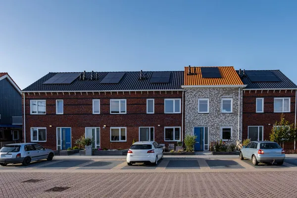 Νεόδμητα σπίτια με ηλιακούς συλλέκτες που συνδέονται στην οροφή κατά ένα ηλιόλουστο ουρανό Κοντινό πλάνο του νέου κτιρίου με μαύρα ηλιακά πάνελ. Zonnepanelen, Zonne energie, Μετάφραση: Ηλιακός πίνακας,, Sun Energy — Φωτογραφία Αρχείου