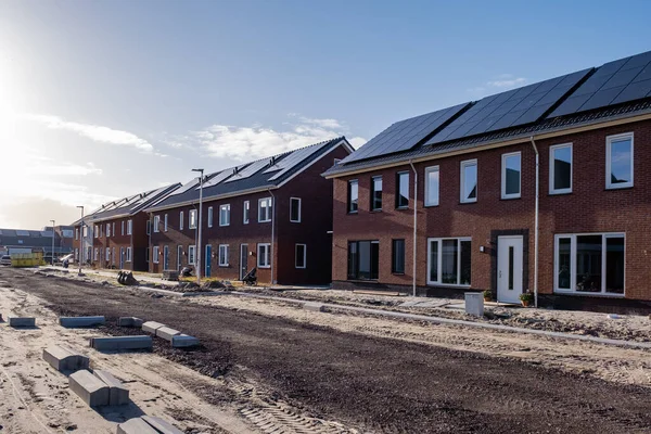 Nově postavené domy se solárními panely připevněnými na střeše proti slunné obloze Zavřít novou budovu s černými solárními panely. Zonnepanelen, Zonne energie, Překlad: Solární panel,, Sun Energy — Stock fotografie