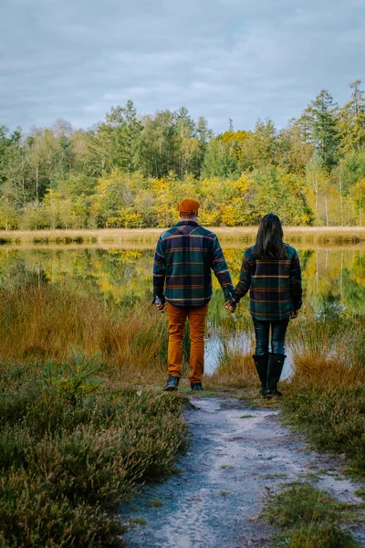 Par man och kvinna medelåldern promenader i skogen under höstsäsongen i naturen vandring med orange röda färgträd under höstsäsongen i Nederländerna Drentsche Aa — Stockfoto