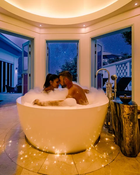 Paar man en vrouw van middelbare leeftijd op vakantie in luxe resort zitten in het bad op zoek naar oceaan, Europese man en Aziatische vrouw in badkuip — Stockfoto