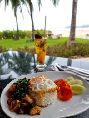 Okyanus kıyısındaki lüks restoranda et ve salatalı yemek tabağı.