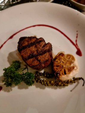 Okyanus kıyısındaki lüks restoranda et ve salatalı yemek tabağı.