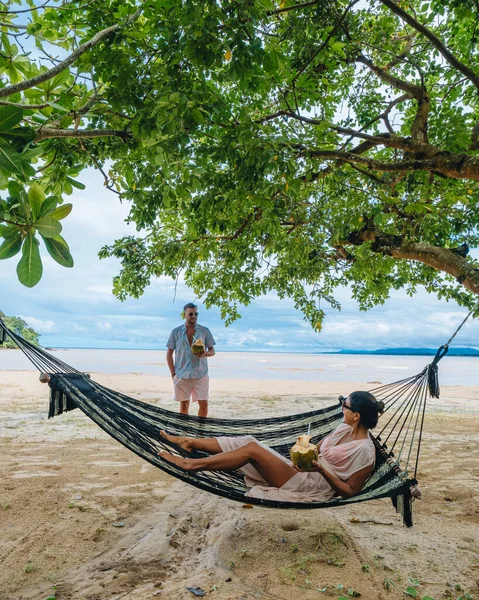 在泰国普吉海滩上的一个吊床上放松一下，一对男女在泰国度过了一个奢华的假期 — 图库照片