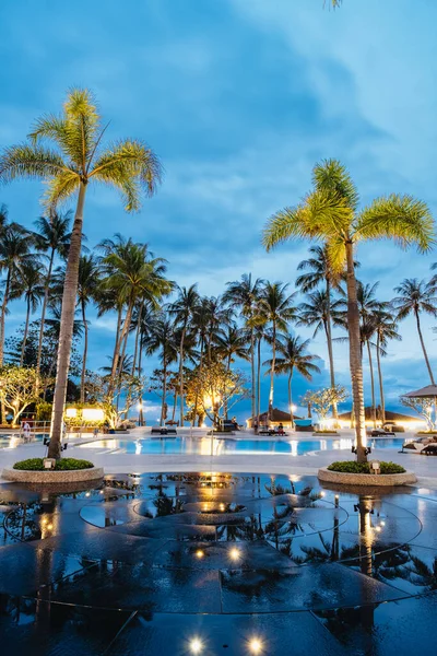 Piscina de luxo com palmeiras à noite durante o pôr do sol na Tailândia — Fotografia de Stock