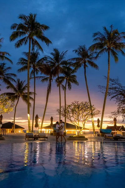 Piscina de luxo com palmeiras à noite durante o pôr do sol na Tailândia — Fotografia de Stock