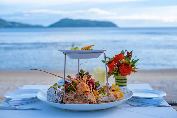 바닷가에서 바닷가재 해산물, 고기, 샐러드와 함께 낭만적 인 저녁 식사를 하는 모습 — 스톡 사진