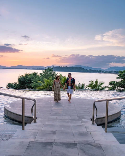 Paar man en vrouw middelbare leeftijd in het zwembad op een luxe vakantie in Thailand, mannen en Aziatische vrouw in het zwembad kijken uit over de baai kijken zonsondergang — Stockfoto