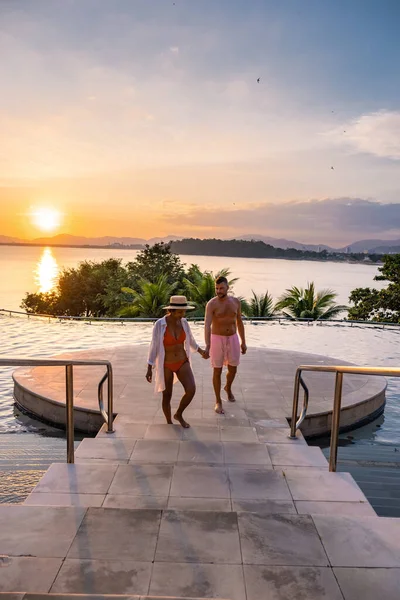 Coppia uomo e donna di mezza età in piscina in una vacanza di lusso in Thailandia, uomini e donne asiatiche in piscina con vista sulla baia guardando il tramonto — Foto Stock