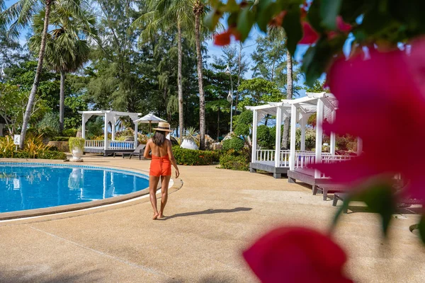 Paar man en vrouw bij zwembad tijdens vakantie in Thailand Phuket, mannen en vrouw van middelbare leeftijd bij het zwembad in Thailand met ligbedden en stoelen en palmbomen — Stockfoto