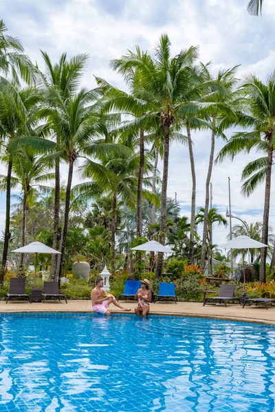 Coppia uomo e donna in piscina durante le vacanze in Thailandia Phuket, uomini e donne di mezza età in piscina in Thailandia con lettini e sedie e palme — Foto Stock
