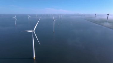 Sabahın erken saatlerinde rüzgar türbinleri, Hollanda 'da rüzgar değirmeni parkı. Hava manzaralı rüzgar türbini, rüzgar parkı batı manzaralı drone manzaralı IJsselmeer gölündeki bir yel değirmeni çiftliği.