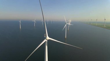 Sabahın erken saatlerinde rüzgar türbinleri, Hollanda 'da rüzgar değirmeni parkı. Hava manzaralı rüzgar türbini, rüzgar parkı batı manzaralı drone manzaralı IJsselmeer gölündeki bir yel değirmeni çiftliği.