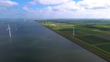 Sabahın erken saatlerinde rüzgar türbinleri, Hollanda 'da rüzgar değirmeni parkı. Hava manzaralı rüzgar türbini, rüzgar parkı batı manzaralı drone manzaralı IJsselmeer gölündeki bir yel değirmeni çiftliği.