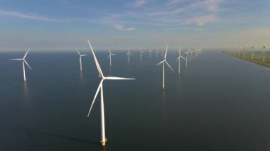 Sabahın erken saatlerinde rüzgar türbinleri, Hollanda 'da rüzgar değirmeni parkı. Hava manzaralı rüzgar türbini, rüzgar parkı batı manzaralı drone manzaralı IJsselmeer gölündeki bir yel değirmeni çiftliği.
