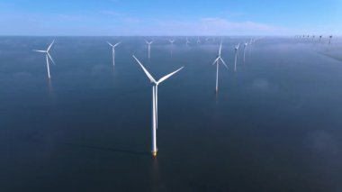 Sabahın erken saatlerinde rüzgar türbinleri, Hollanda 'da rüzgar değirmeni parkı. Hava manzaralı rüzgar türbini, rüzgar parkı batı manzaralı drone manzaralı IJsselmeer gölündeki bir yel değirmeni çiftliği.