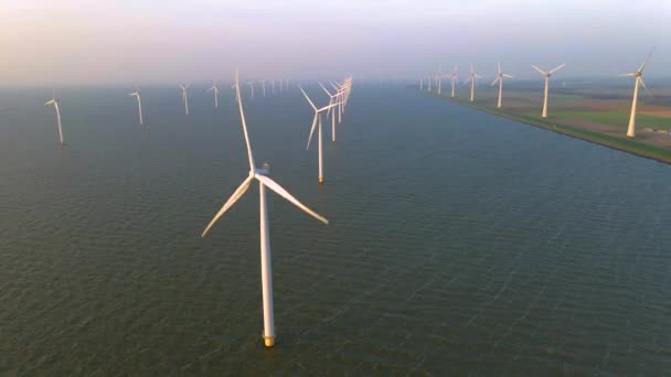 Windturbines in de vroege ochtend, windmolenpark in Nederland. Windturbine vanuit de lucht, Uitzicht op Drone bij windpark westermeerdijk een windmolenpark in het IJsselmeer de grootste in de — Stockvideo