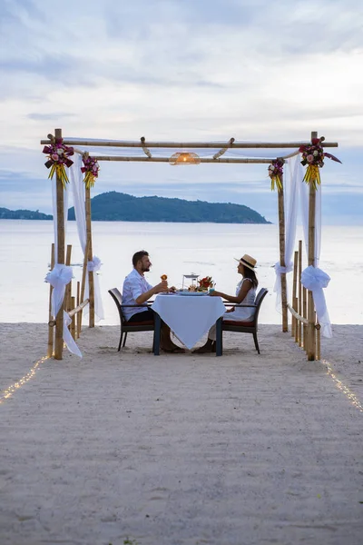 Jantar romântico na praia em Phuket Tailândia, casal homem e mulher de meia idade mulher asiática e homem europeu ter um jantar na praia na Tailândia durante o pôr do sol — Fotografia de Stock