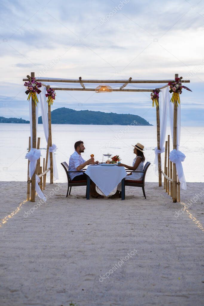Romantic dinner on the beach in Phuket Thailand, couple man and woman mid age Asian woman and European man having a dinner on the beach in Thailand during sunset