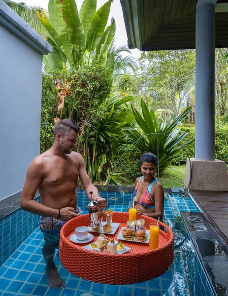 Couple homme et femme avoir flottant petit déjeuner thé élevé dans la piscine en face de leur bungalow — Photo