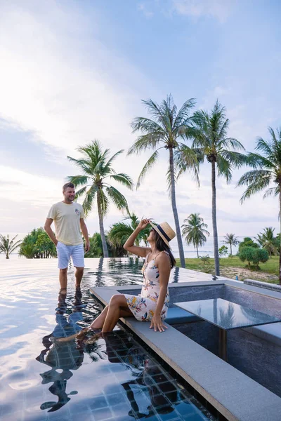 Paar beobachtet Sonnenuntergang von einem Infinity-Pool auf dem Dach in einem Luxus-Urlaub — Stockfoto