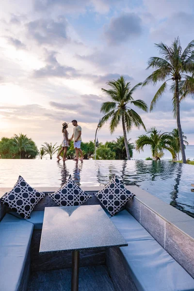 Couple homme et femme regarder coucher de soleil à partir d'une piscine à débordement sur le toit pendant des vacances de luxe — Photo