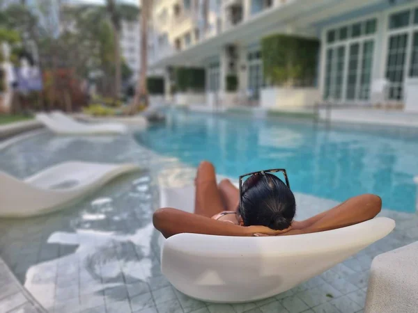 Selective focus of woman relaxing in a chair in swimming pool — Stock Photo, Image