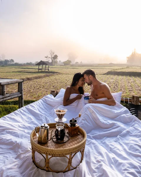 Casal homem e mulher na cama olhando para fora sobre o campo de arrozais no norte da Tailândia Nan — Fotografia de Stock