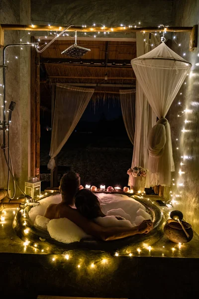 Couple in bathroom in bath tub at night with christmas lights, man and woman mid age having romantic night in bath tub in Nan Thailand — стоковое фото